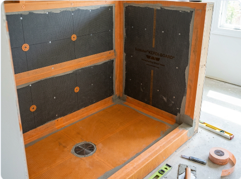 High-performance waterproofing membrane being installed in a custom tile shower base